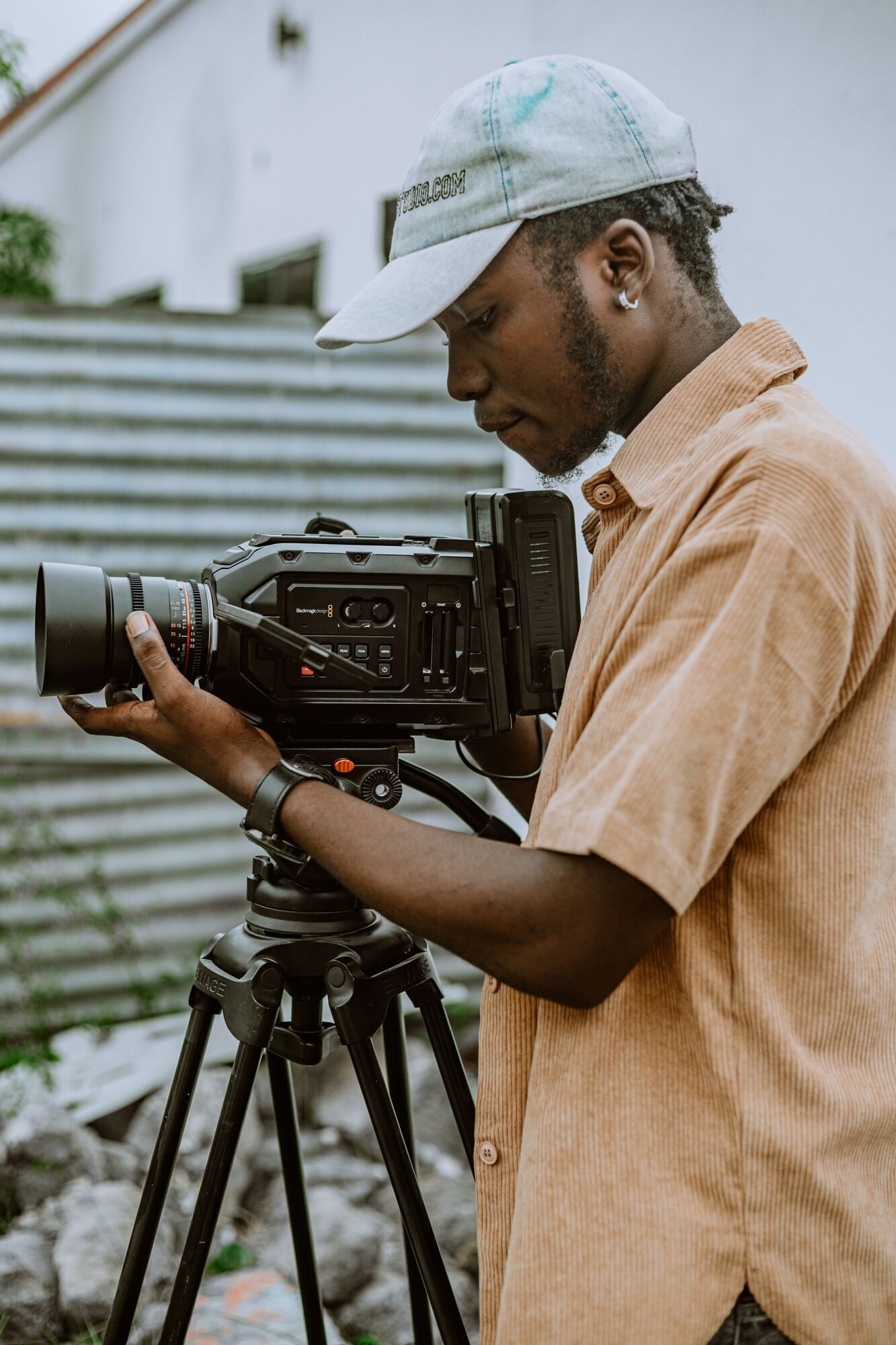A camera operator adjusts a cinema camera mounted on a tripod.