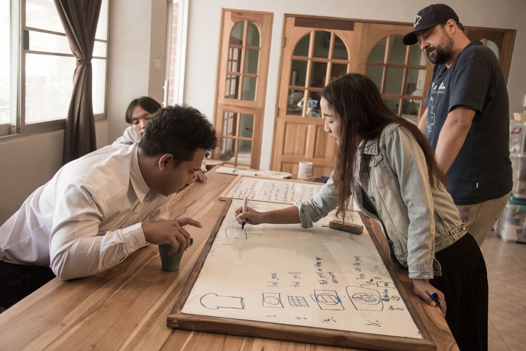 A small team gathers around a whiteboard, sketching out a shared plan together.