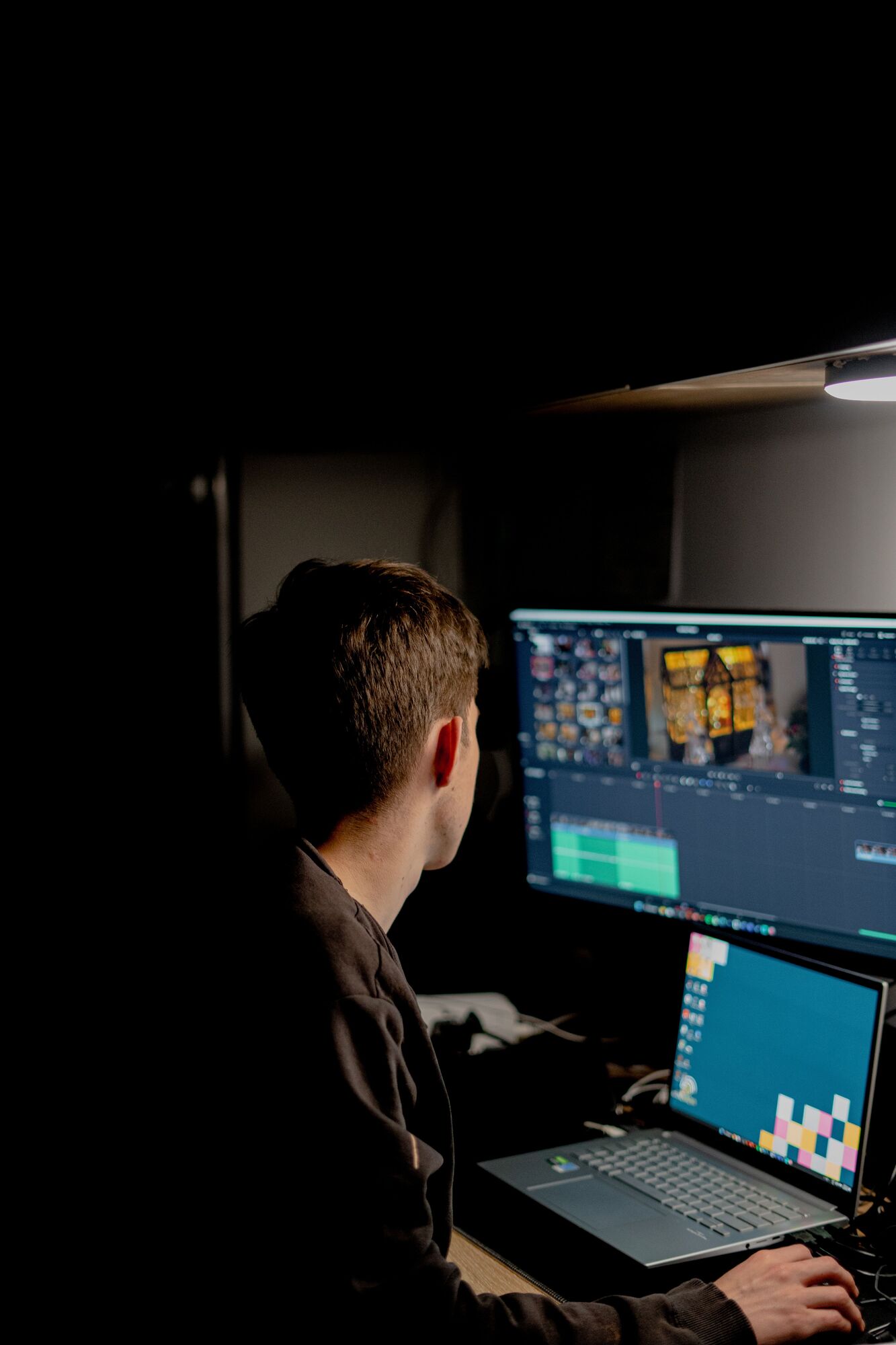 An editor works alone at night, lit only by their monitor.