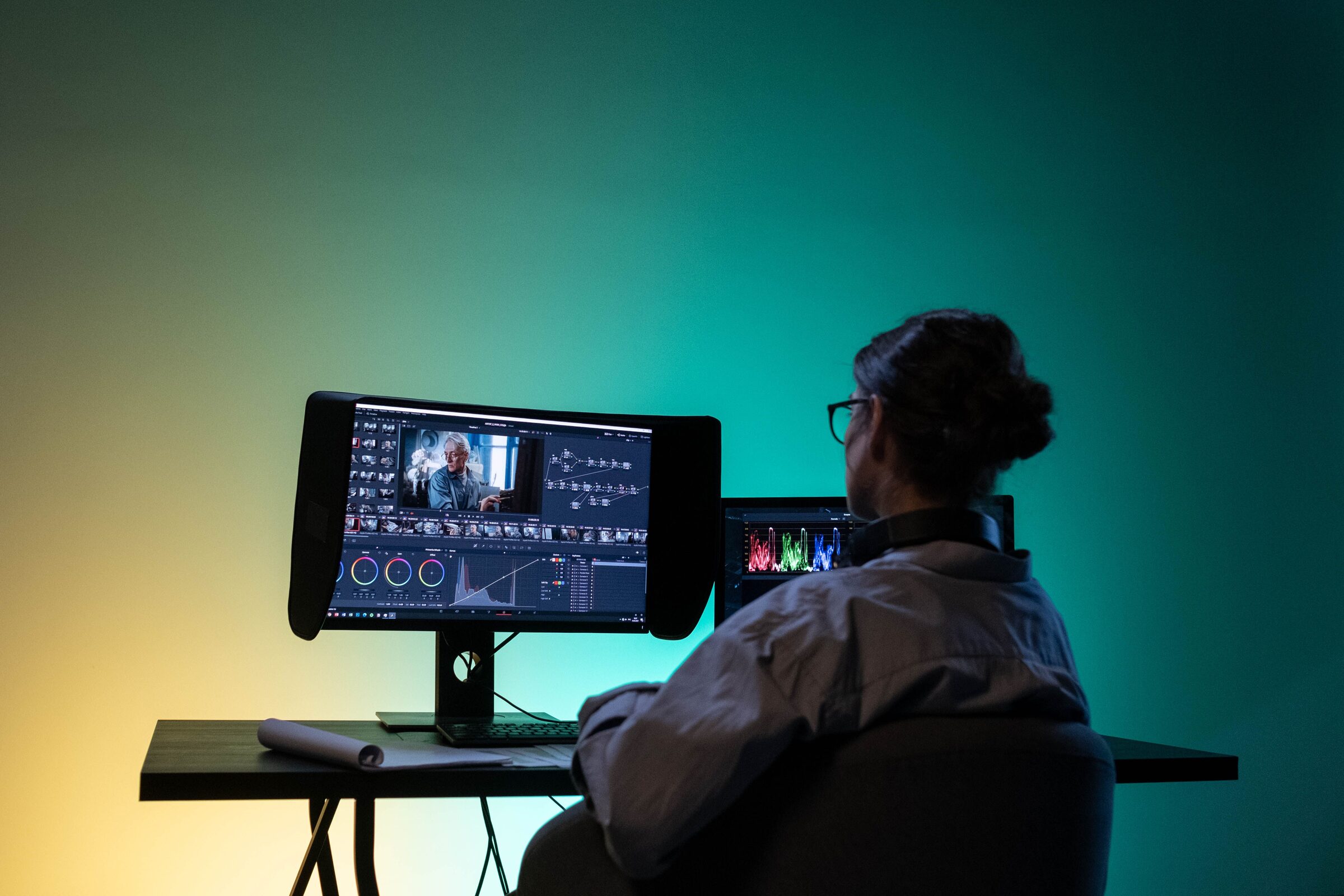 A colorist reviews color wheels and a waveform scope on a dedicated grading display.