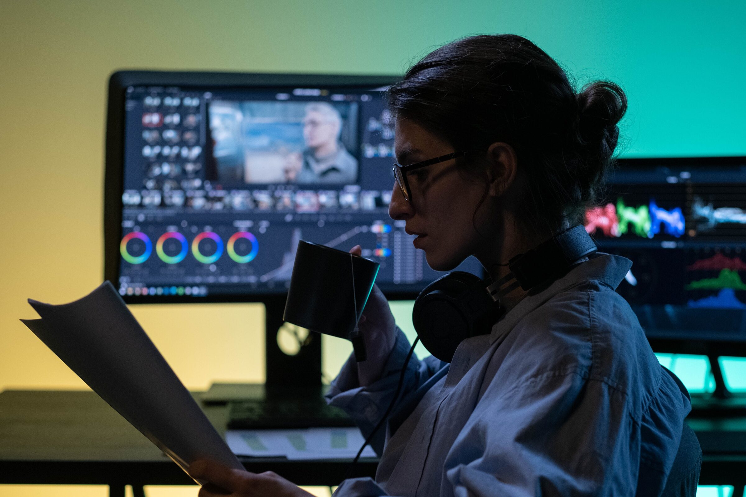 A colorist studies handwritten notes beside a color-grading monitor and reference scopes.
