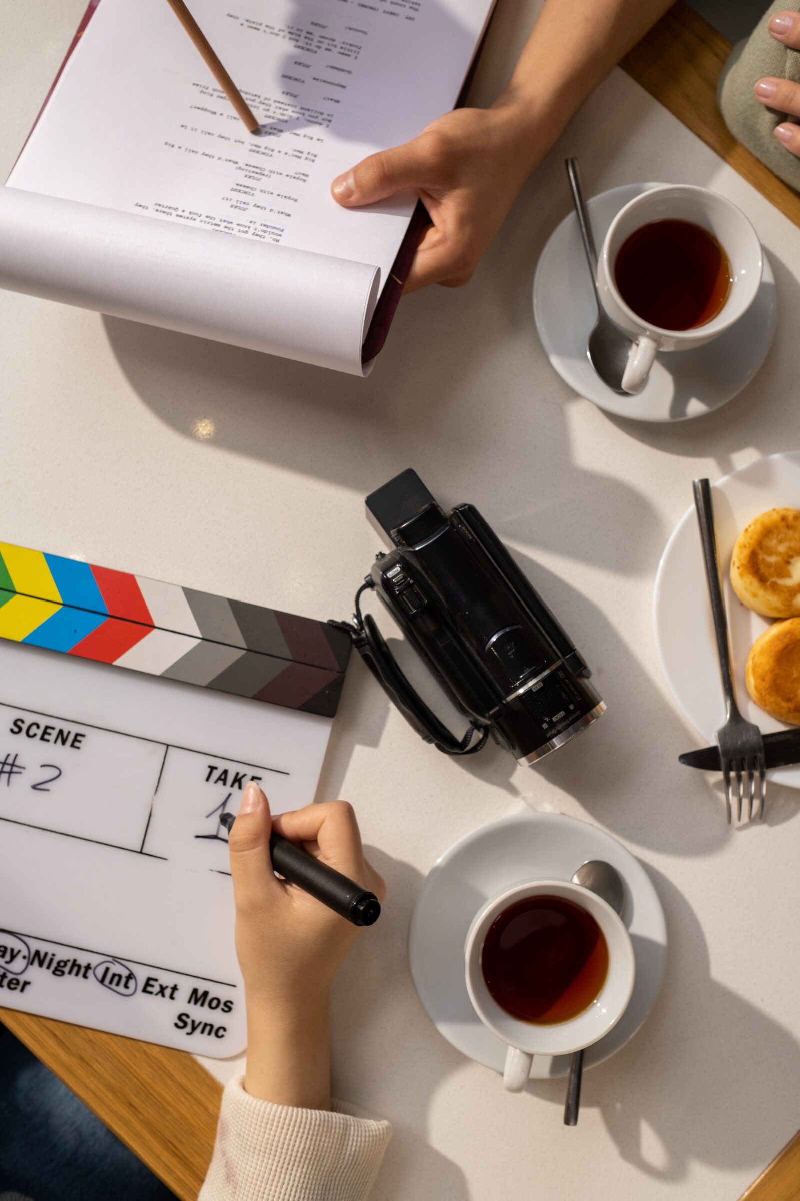 A clapperboard, a vintage camcorder, and a marked-up script laid out before a shoot.